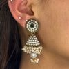 Close-up of an ear wearing a decorative pearl earring with gold accents.