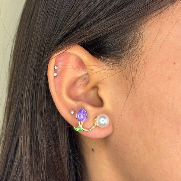 Close-up of an ear with multiple earrings against a neutral background