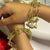 Gold bracelets on a person's wrist with a plant in the background